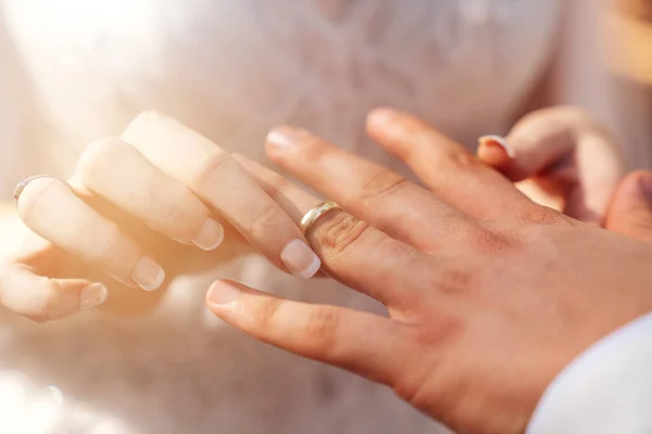 Bruid en bruidegom handen bij elkaar en bruid zetten trouwring aan bruidegoms hand als symbool van hechting — Stockfoto