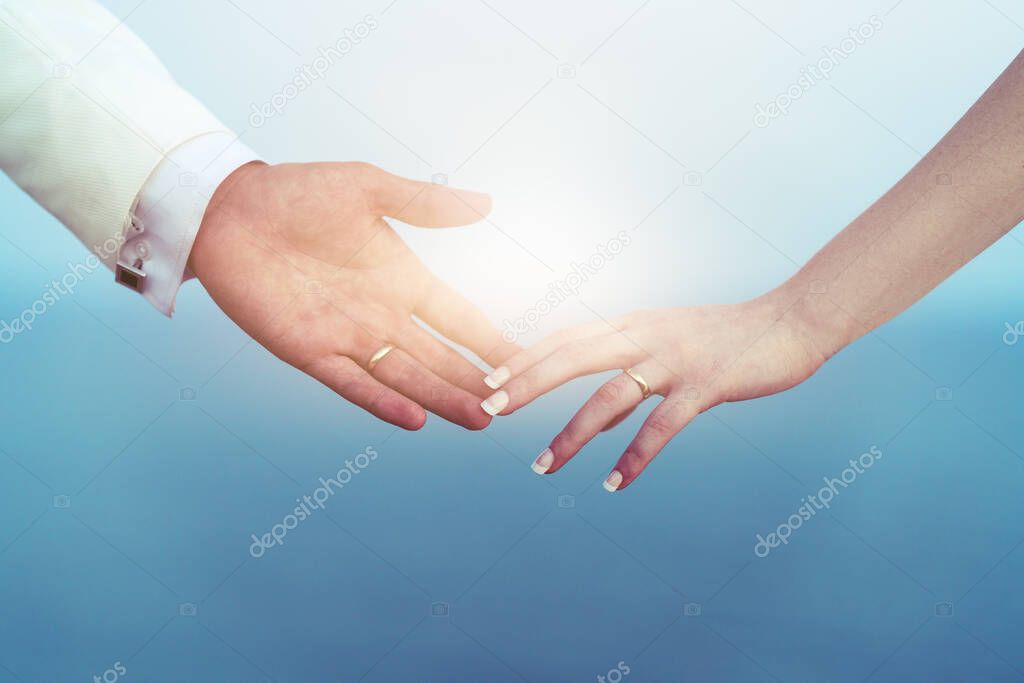 Bride and groom hands together and fingers touching eachother with wedding ring as a symbol of bonding.