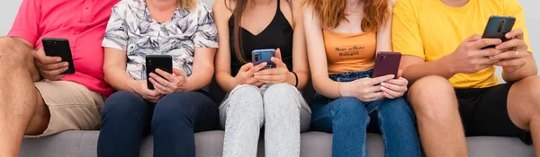 Un grup de prieteni care stau pe canapea și se uită la telefoanele mobile. Conceptul de dependență tehnologică . — Fotografie, imagine de stoc