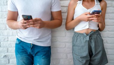 İki arkadaş ya da sevgili kapının önünde dikilip cep telefonlarına bakıyorlar. Teknoloji bağımlılığı kavramı.