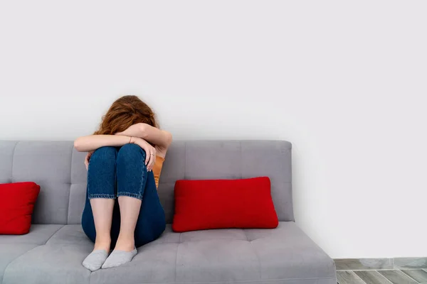 Triste joven mujer es sentado en el couach poner su cabeza en rodillas mientras ella llorando. — Foto de Stock