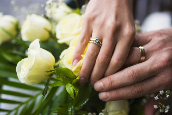 Hände und Ringe am Brautstrauß — Stockfoto