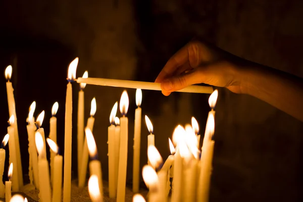 Candele di illuminazione a mano donna in una chiesa — Foto Stock