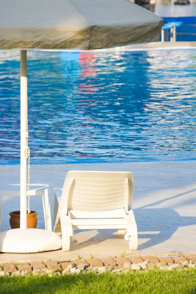 Židle s bílým deštníkem u bazénu — Stock fotografie