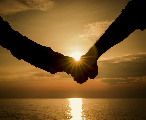 Silhouettes couples hands on sunset
