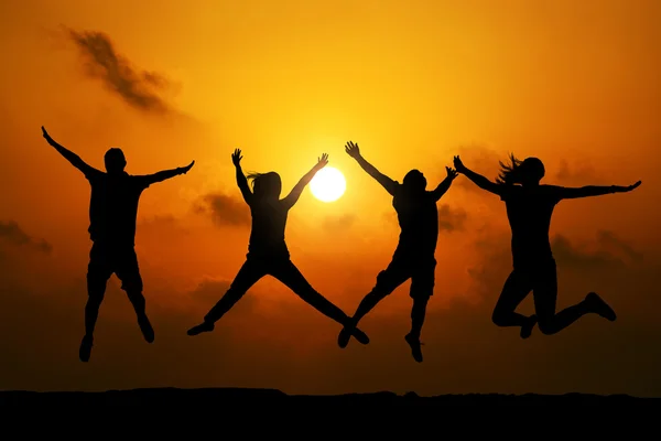 Vier Freunde springen bei Sonnenuntergang — Stockfoto