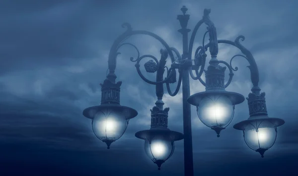 Street lamp shining at night against cloudy sky — Stock Photo, Image