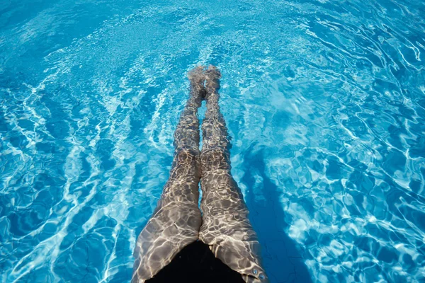 Sexy vrouwen benen spetteren in zwembad — Stockfoto