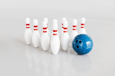 Blue Bowling Ball Approaching Pins on White Background. High quality photo
