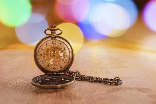 Retro clock with bokeh on wooden background