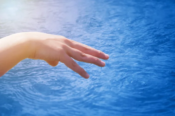 Mano descansando chica en un fondo de bluethermal piscina de agua — Foto de Stock