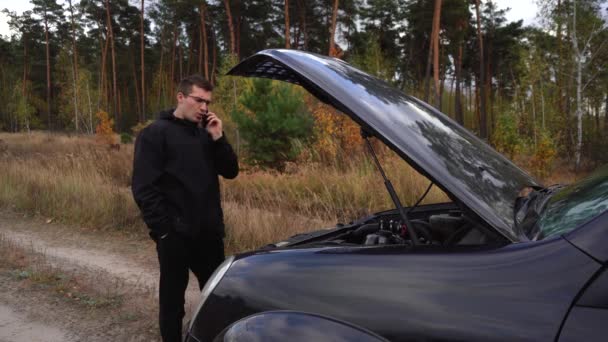 Muž mluví po telefonu kolem rozbitého auta. — Stock video