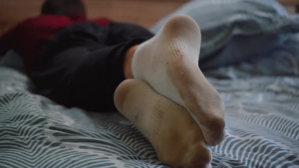 Man in dirty socks is lying on the bed — Stock Video