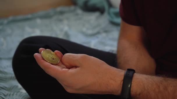 Hombre sostiene una moneda bitcoin en su mano y la aprieta — Vídeo de stock