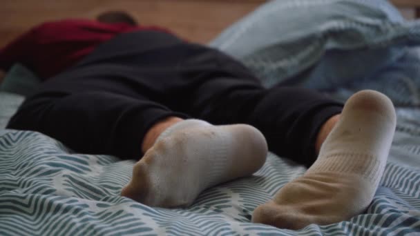 Hombre en calcetines blancos sucios está acostado en la cama — Vídeos de Stock