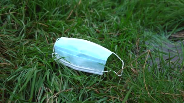 Медицинская маска лежит на зеленой траве — стоковое видео