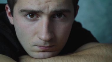 Adam elinde uzanmış kameraya bakıyor..