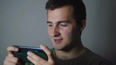 Gri arka planda telefonla oynayan adam