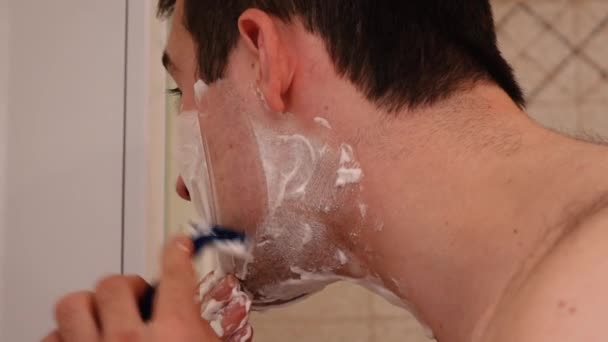 Мужчина бреется утром перед работой в ванной комнате — стоковое видео