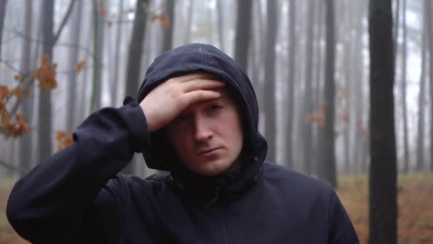 Мужчина снимает капюшон в туманном лесу — стоковое видео