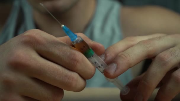 A man holding a syringe with a drug in his hands. addiction concept — Stock Video