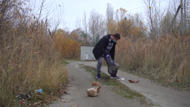 Człowiek zbiera śmieci do worka na śmieci — Wideo stockowe