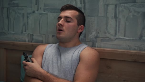 Мужчина курит вапе, лежа на кровати — стоковое видео
