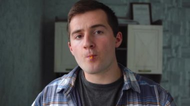 Adam lolipopu emer ve kameraya bakar.