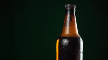 Siyah arka planda bir şişe bira duruyor.
