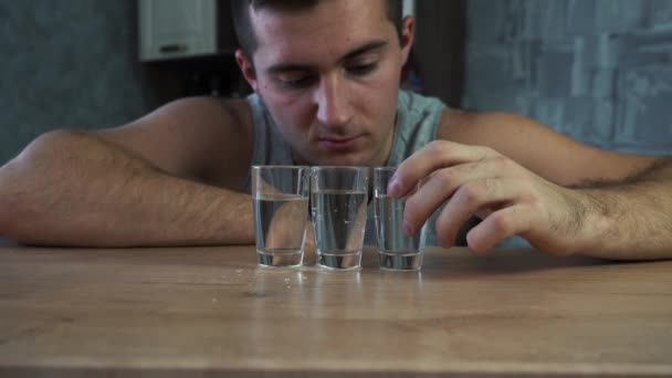 Berusad alkohol sitter vid bordet och tittar på vodka — Stockvideo