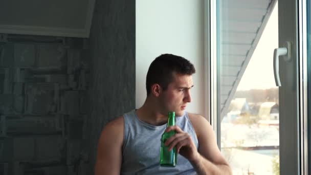 Man die bier en flessen drinkt zittend bij het raam — Stockvideo