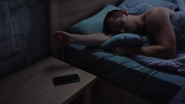 Uykucu adam telefondaki alarmı kapatıyor.