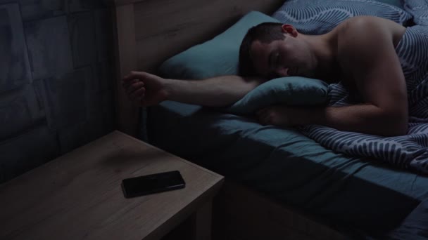 Hombre somnoliento apaga la alarma en el teléfono — Vídeo de stock