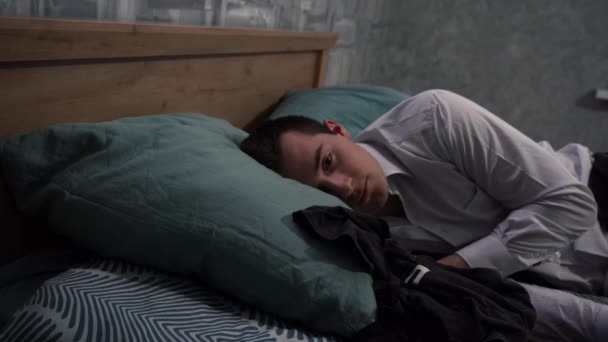 一个疲惫的人躺在床上的一套衣服里 — 图库视频影像