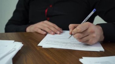 Erkek işadamı ofisinde masasında otururken kağıt dolduruyor.