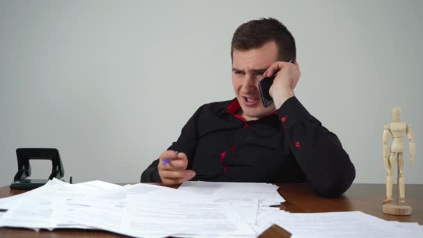 Muž obchodník mluví do telefonu, zatímco sedí u stolu v kanceláři — Stock video