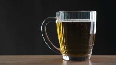 Siyah arka planda duran bir bardak bira.