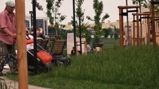 Han klipper gräsmattan i parken. Ryssland Moskva 20 juli 2020 — Stockvideo