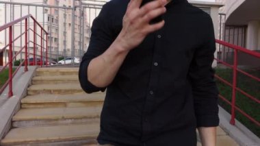 Adam sokakta yürüyor ve telefonla konuşuyor.