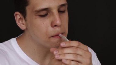 Bir adam sigarayı yakar ve içer.