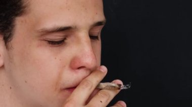 Adam siyah arka planda ağır çekimde sigara içiyor...