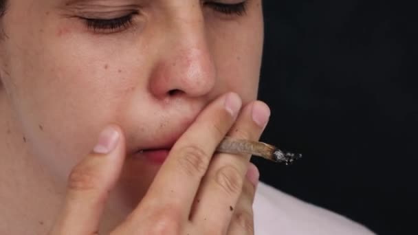 Un bărbat fumează o țigară în mișcare lentă pe un fundal negru — Videoclip de stoc