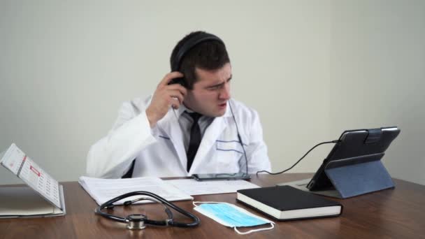 Чоловічий лікар чхає і розмовляє з пацієнтами через відеозв'язок — стокове відео