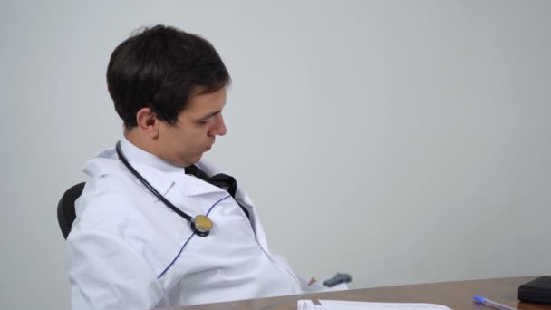 Γιατρός κάθεται στο τραπέζι μιλώντας στο τηλέφωνο — Αρχείο Βίντεο