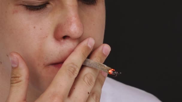 Человек курит сигарету в замедленной съемке на черном фоне — стоковое видео