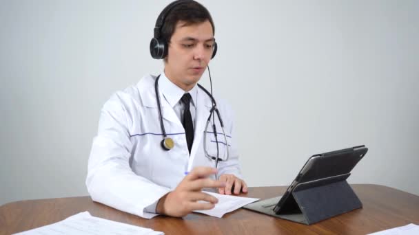 Лікар спілкується через відеозв'язок, сидячи в своєму офісі — стокове відео