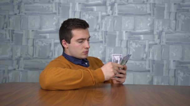 Ein Mann zählt Geld, während er am Tisch sitzt — Stockvideo