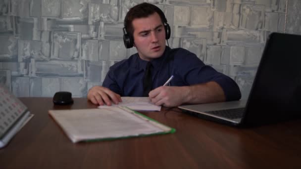 Чоловік заповнює папір, сидячи на своєму робочому місці — стокове відео