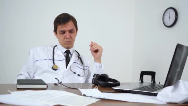 Доктор принимает таблетки, сидя за столом — стоковое видео