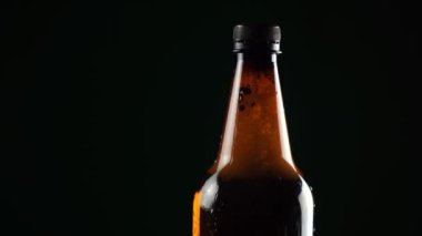 Siyah arka planda bira olan plastik şişe.